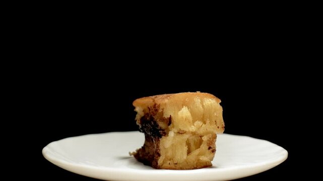 A slice of Terang Bulan or Martabak Manis on a white plate with black background