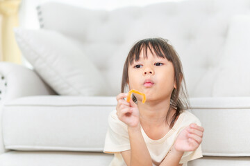 Happy girl with candy in living room, Asian kid girl eat sweet candy
