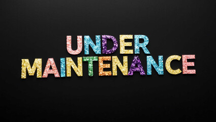 Obraz premium under maintenance word lettering made of colorful glitter shining effect on plain black background