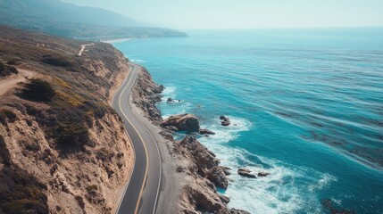 Fototapeta premium A scenic coastal road with waves crashing against rocky cliffs, the ocean stretching out toward the