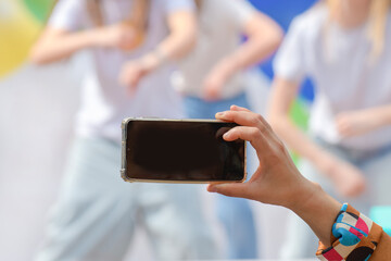 Taking photos with your phone. The hand of a person filming a children's party