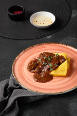 Rustic Polenta with Braised Beef Cheeks on Pink Plate in Dim Lighting for Noir Cuisine Photography