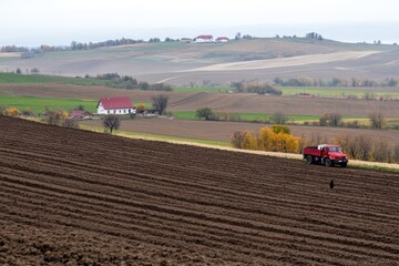 a Belarusian village scene during potato harvest cottages rural farming agricultural community barns autumn countryside fields full of people working captured in the soft light of an autumn afternoon