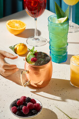 Stylish Alcoholic Lime and Gin Mule in a Copper Mug Lemons, Berries, and Colorful Cocktails on Light Table