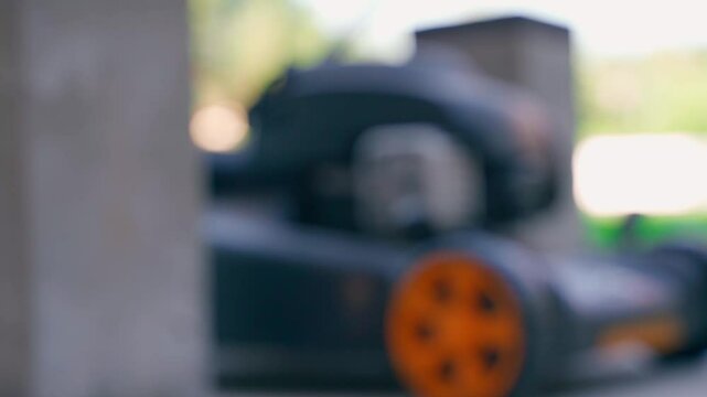 A hand puts a freshly prepared red oil-fuel mixture on a background of garden equipment. Gardener prepared fuel for cutting grass, close-up