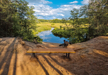 Fototapeta premium Small river flowing among fields, forests and its infrastructure.