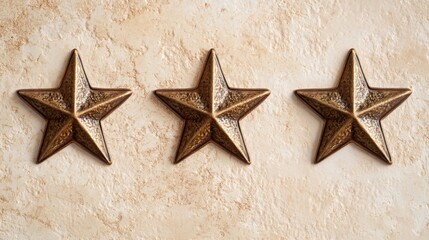 Three bronze five-pointed stars are positioned in a straight line against a light, textured background. Their shiny surfaces reflect light, creating an appealing contrast with the backdrop.