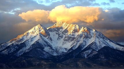 A majestic mountain range with snow-capped peaks and a large, golden cloud above.