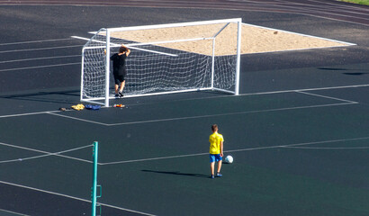 Obraz premium A boy in a yellow shirt is playing soccer on a field
