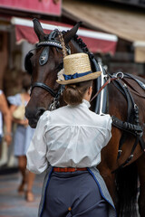 Chica joven vestida de &eacute;poca junto a su carruaje