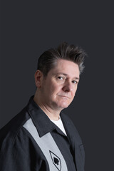 Portrait of a serious looking mature man with nice hair with some gray hair, looking at camera. Dark background. Copy space. Concept of men and maturity