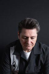 Portrait of a sad and sorrowful mature man looking down on dark background. Copy space. Concept of sadness, depression and mental health