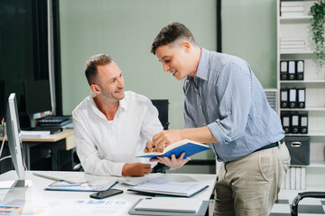 Two business workers talking on the smartphone and using laptop