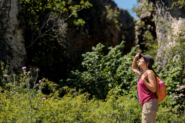 Young woman enjoying nature.Hiking in the mountains, observing the landscape.Doing sports and physical activity.Let's take care of our natural surroundings and our environment.Moments of disconnection