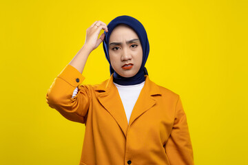 Frustrated Asian woman scratching head isolated on yellow background