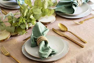 Elegant Festive table setting, white plates, gold cutlery, green napkin and centrepiece . Tableware...