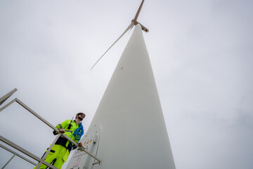 Maintenance engineer working at wind turbine farm. Windturbine inspector wearing Personal protective equipment working at wind turbines farm