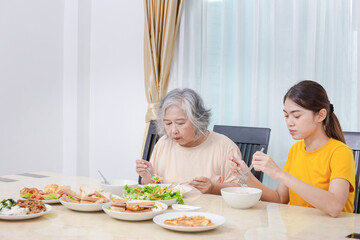 Mother and adult daughter eating meal together, Senior woman and daughter having breakfast in morning together