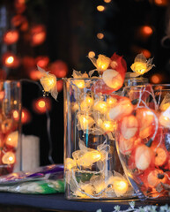 A table with a few vases of different sizes and shapes with Christmas lights 