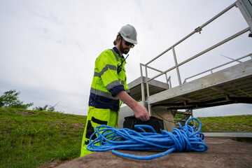 Windturbine inspector wearing Personal protective equipment working at wind turbines farm