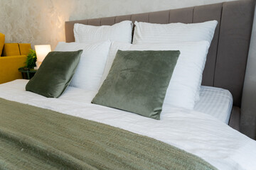 A cozy hotel room features a bed with white sheets and green pillows