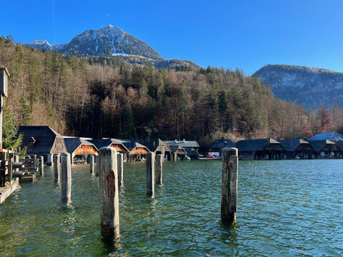 The boathouse on Königssee lake, viewed from the port, with the alpine forest and majestic mountain range in the background. A peaceful scene in Berchtesgaden, Germany.