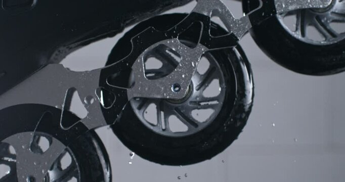 Super slow motion close up of wet inline roller sports skates wheels rotating with energetic movement with splashing water drops isolated on dark background at 1000 fps.
