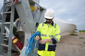 Windturbine inspector wearing Personal protective equipment working at wind turbines farm