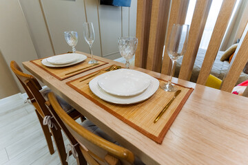 A beautifully crafted wooden dining table adorned with elegant plates, sparkling wine glasses, and a warm ambiance invited guests to enjoy their meal with an inviting atmosphere