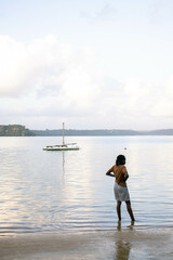 A  young black woman standing by the beach early in the morning.