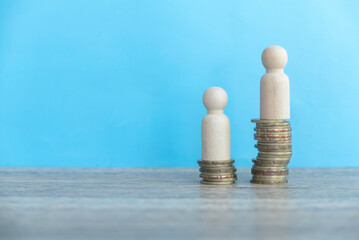 Coins ascending stack with people on top over a blue wall.