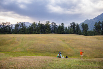 Two happy male friends spending leisure time and lying down in a green grass at park in Tirthan Valley,Shangarh himanchal pradesh india. 