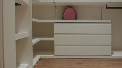 A Modern Minimalist Closet designed with Drawers and featuring a stylish Pink Backpack