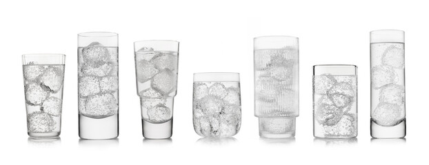 Obraz premium Water sparkling lemonade drink with ice cubes in various shape and size glasses on white background.