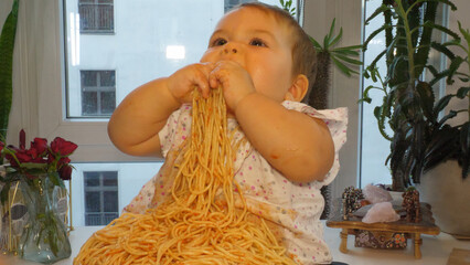 Baby girl eating pasta with the hands