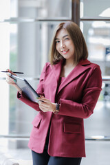 A woman stands using a tablet to work and thinks of ideas.