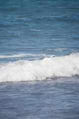 Blue sea with crashing waves and shimmering reflections on the water