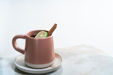 A mug of hot lemon tea with cinnamon on granite table.
