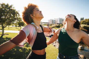 Sisters enjoying the sun on their faces, expressing freedom and happiness in a park setting with...