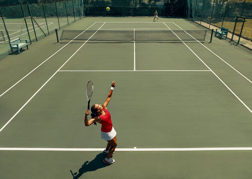 Female tennis player serving during match on hardcourt
