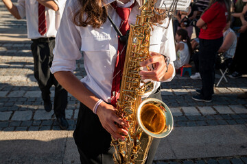 Saxofonista a tocar numa orquestra musical enquanto acompanha uma procissão religiosa numa festa popular portuguesa