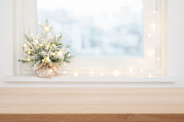 Empty wooden table top in front of blurred Christmas decorated frosty window background