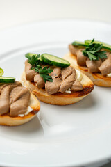 Savory canapes topped with creamy spread and cucumber slices served on toasted bread at a casual gathering