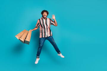Full body portrait of nice young man hold bags jump wear shirt isolated on turquoise color background