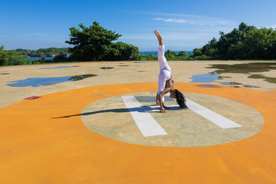Flexible woman doing standing spilts at public park on sunny day