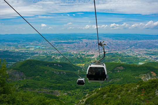 Cable cars ascend Mount Dajti, offering breathtaking panoramic views of the sprawling urban landscape below and the surrounding green countryside. Tirana, Albania