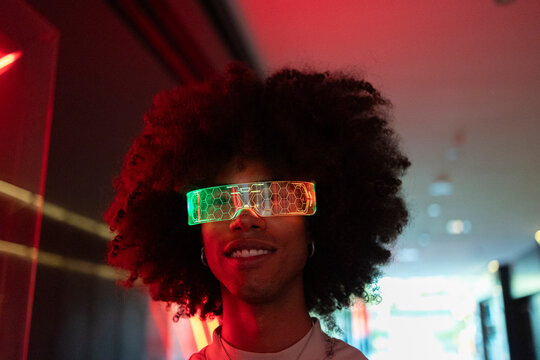 Smiling young man with curly hair wearing colorful smart glasses