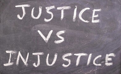 Justice vs Injustice Words Written on Blackboard with White Chalk