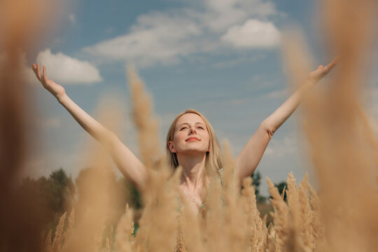 Carefree woman with arms outstretched at reeds field