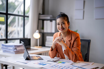 Businesswoman smiling while working with financial documents at office desk